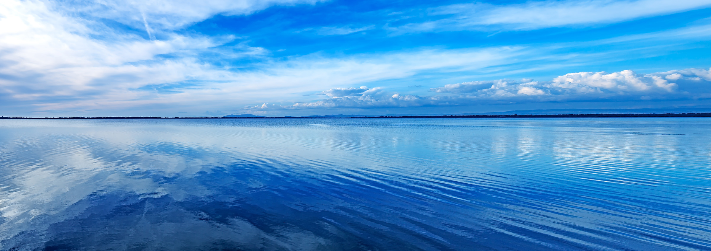 glassy sea with vivd blue sky and white clouds